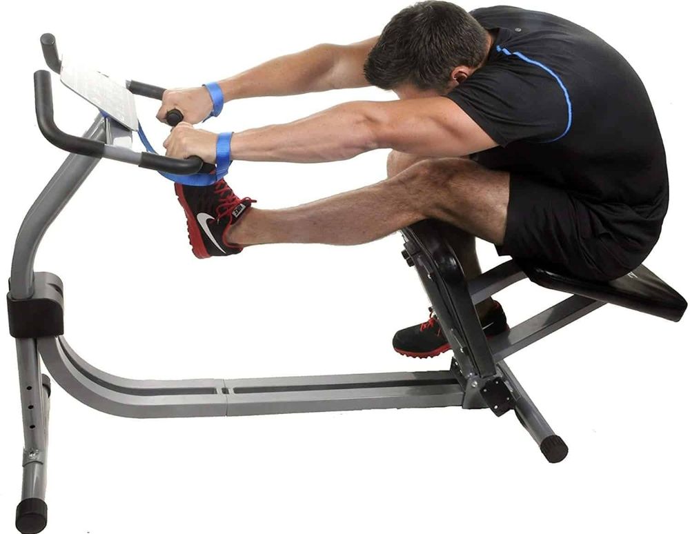 A stock image of a man using a stretching machine. It is shaped like a sideways stretched c, where one end has handlebars the man is gripping and the other has a seat that tilts backwards. The man has one leg extended and the other leg is in a kneeling position on the attached kneepad below the seat. It is used for a variety of deep hip, back, and leg stretches that I find difficult to do if I am just sat on the floor.