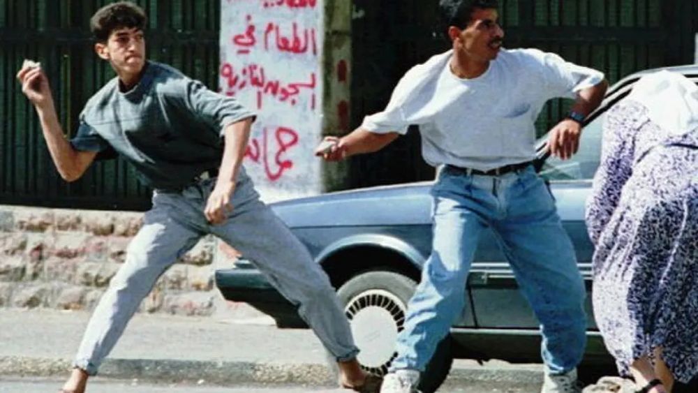 Palestinians throwing rocks on a street.