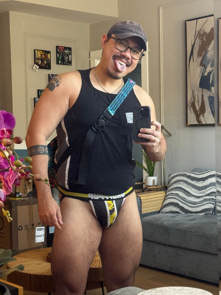 Picture of me in a the mirror wearing a black tank top and black and yellow jockstrap