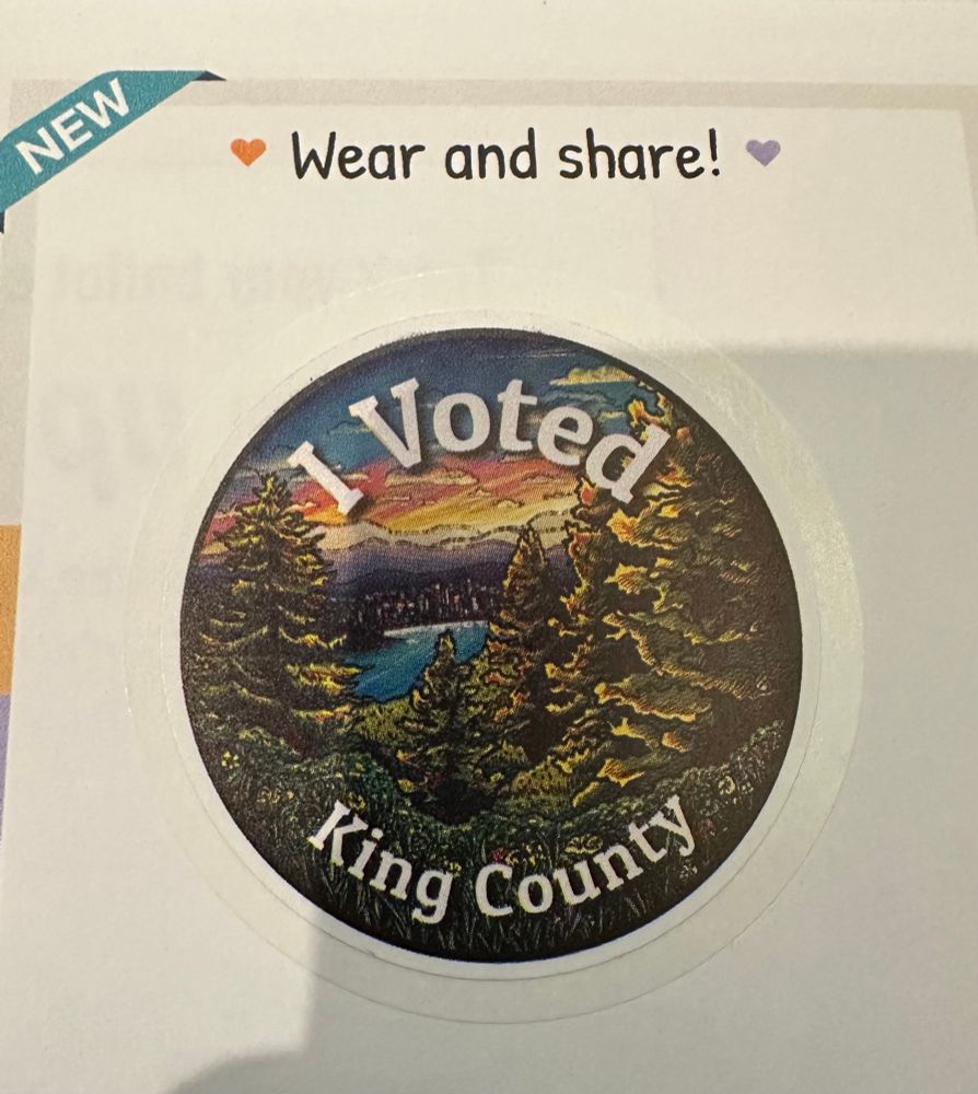Picture of a sticker that says ‘I Voted King County’ with a drawing of evergreens, a body of water, mountains, and a sunset.