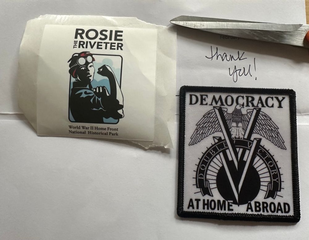 Picture of a sticker and a patch from the World War II Home Front National Historical Park (Rosie the Riveter Trust).  Sticker is a Rosie the Riveter, patch is Democracy At Home Abroad Double-V Victory