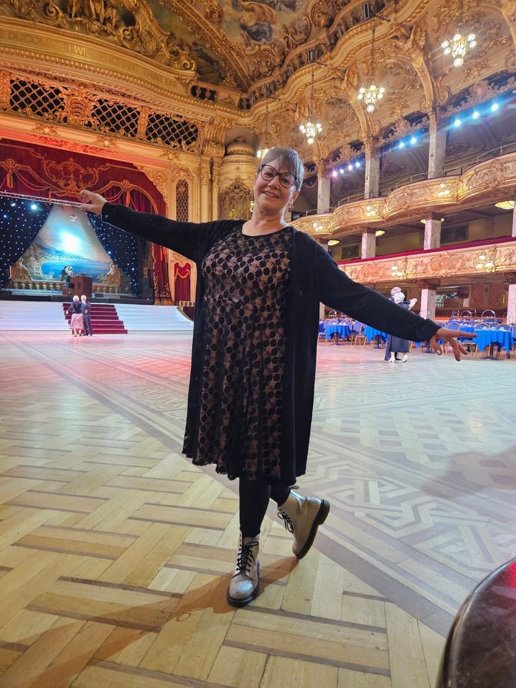 Me on the Blackpool Tower Ballroom dance floor. I am wearing a pink and black lace 3/4 length dress and silver doc martens. Yes I danced in them. Just one circuit before changing into my dancing shoes. 