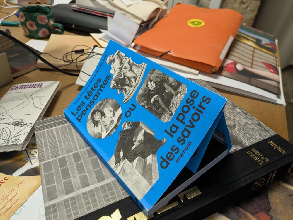 un livre bleu a rabat posé sur un bureau en désordre