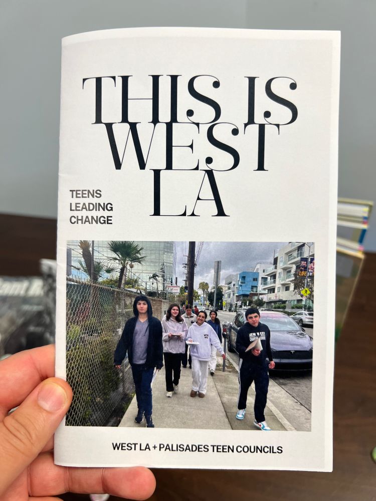 The front cover of a photozine titled "THIS IS WEST LA" created by the Teen Councils of West Los Angeles & Pacific Palisades. The photo shows a group of young people striding down Sawtelle Boulevard in Sawtelle Japantown past Yamaguchi Nursery.