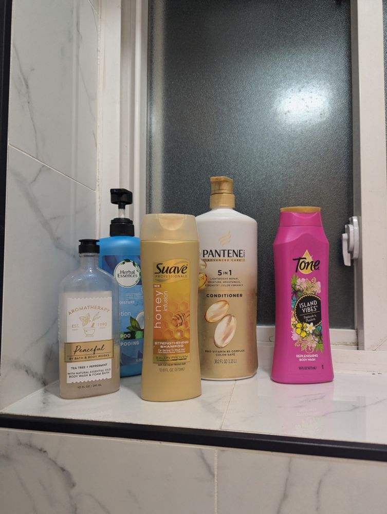 5 bottles of shampoos, conditioners and body washes all varying scents and brands, branding styles clashing merrily