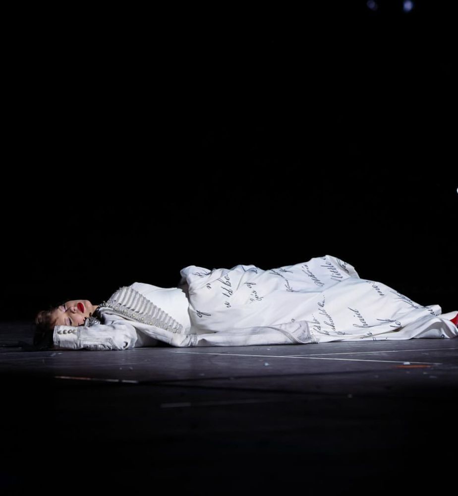 Taylor Swift in TTPD dress lying on the stage eyes closed 