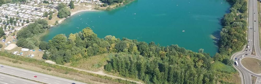 Drohnenbild auf einen Baggersee, gerahmt von zwei Autobahnen
