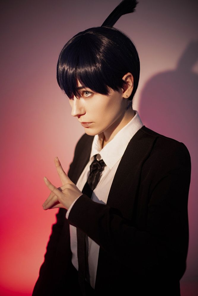 Cosplay of Aki from Chainsaw Man with a red background, looking to the side like he's gonna do some serious business. Also holding his hand in a signature gesture ofc