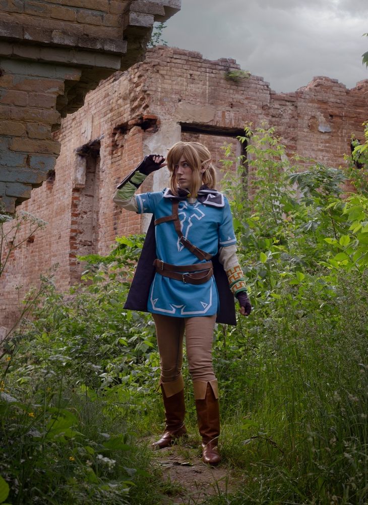 A photo of a Link cosplayer standing in front of some castle or mansion ruins.