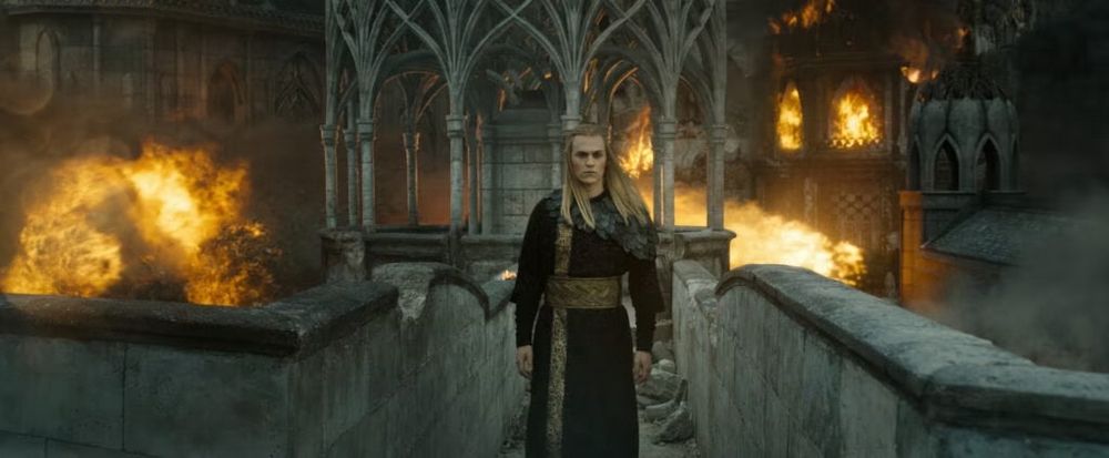 Sauron crosses a bridge as the city burns behind him