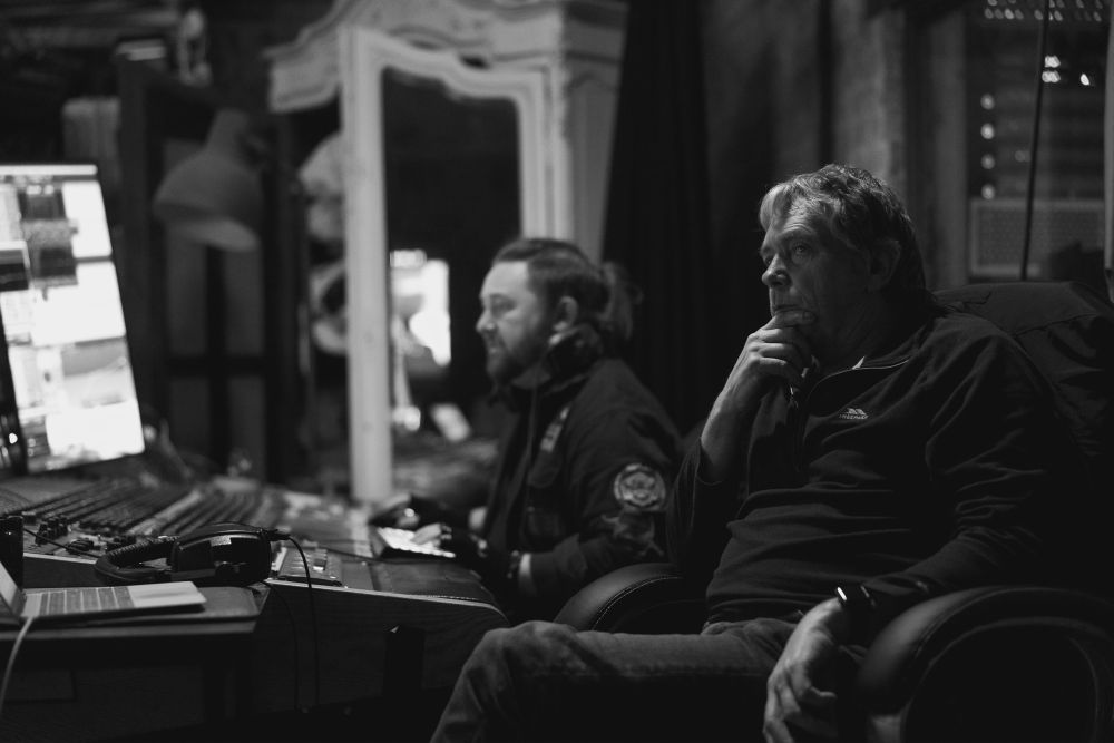 Foley mixer Glen Gathard and foley editor Derek Trigg sit behind mixing desk in foley theatre looking at the screens