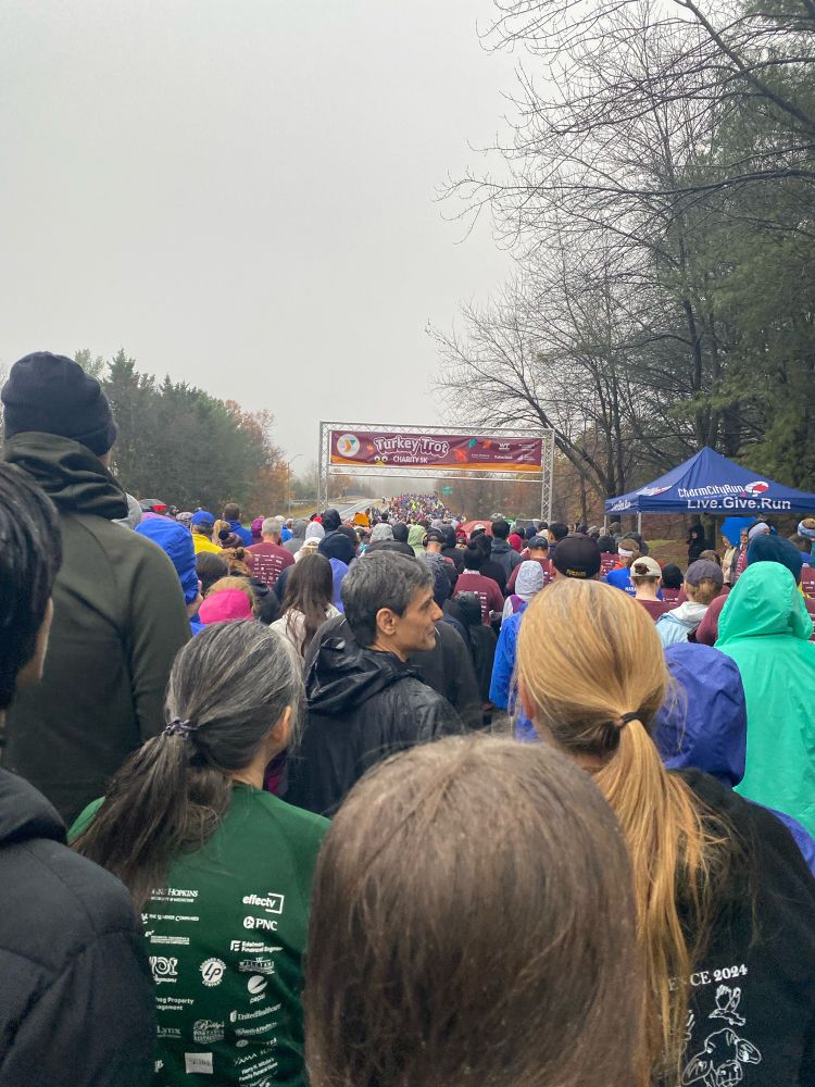 Crowd of runners about to go under a Turkey Trot sign 