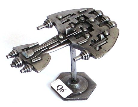 A metal miniature spaceship at 1/3000th scale.

It is quite alien. The front has three coiled lasers up front housed on a shape kind of like a 2d dress? (Sorry I'm really poor at describing things!) Then a thin section that leads to a bigger part that's the same shape. This has 2 lasers either end.

There's various domes and rectangle section on the surface.