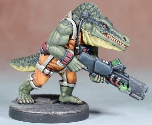 A Sci-Fi miniature of a crocodile humanid/biped. They are wearing an orange jumpsuit and carrying a large futuristic rifle.