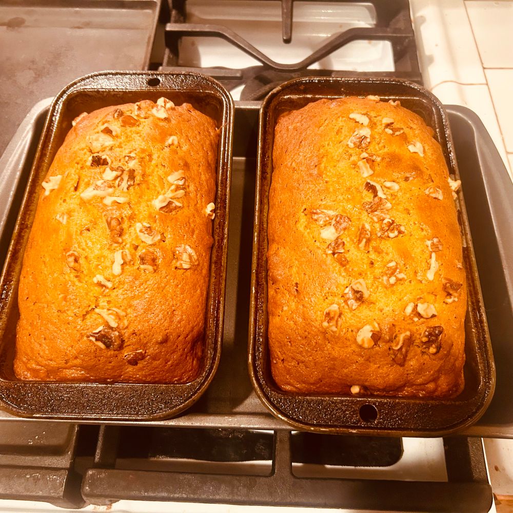 Two loads of pumpkin bread in their baking pans sitting on top of oven