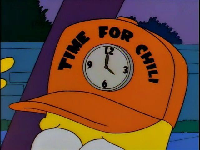 homer simpson motioning towards his “time for chili hat”, which is orange and has a clock set to 4 on it