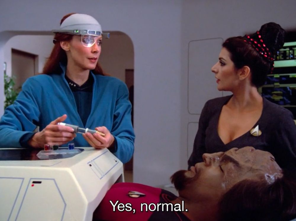 Star Trek: The Next Generation. Dr. Crusher wears a bizarre tech-helmet and holds some sci-fi gadget. She's working on an unconscious Worf and says to Troi "Yes, normal."