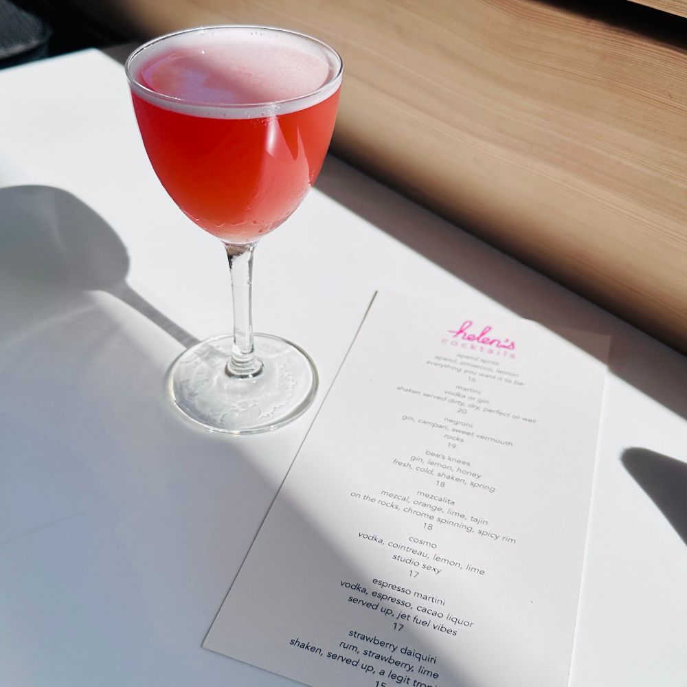 A red cocktail in a tulip glass on a white table 