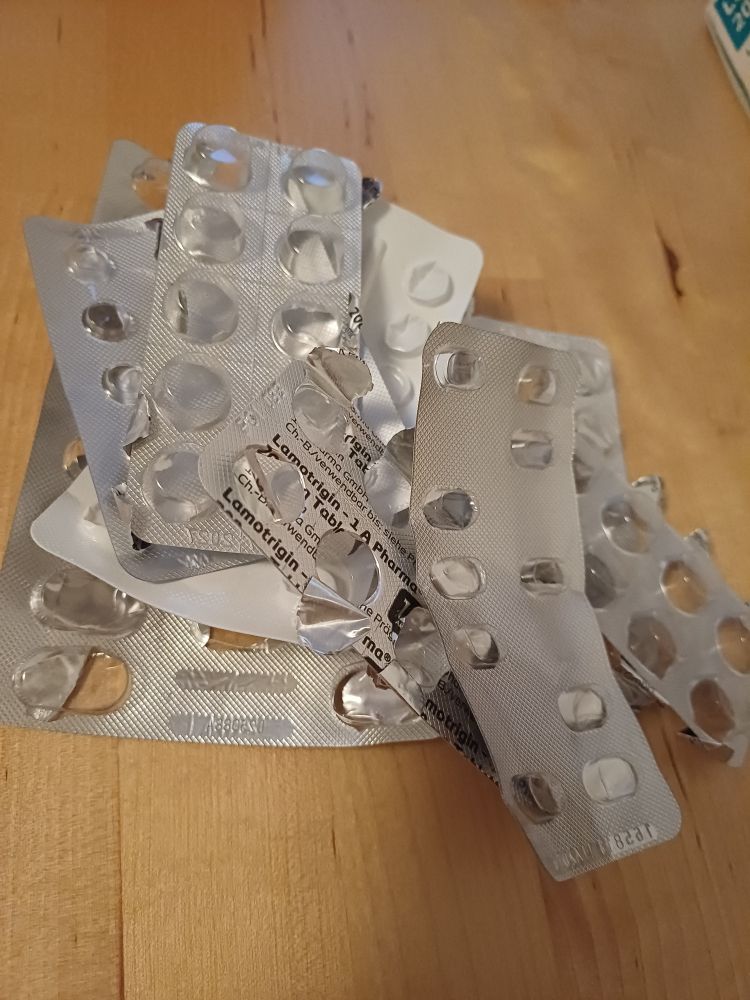 En haug med tomme pillebrett ligger på et bord.