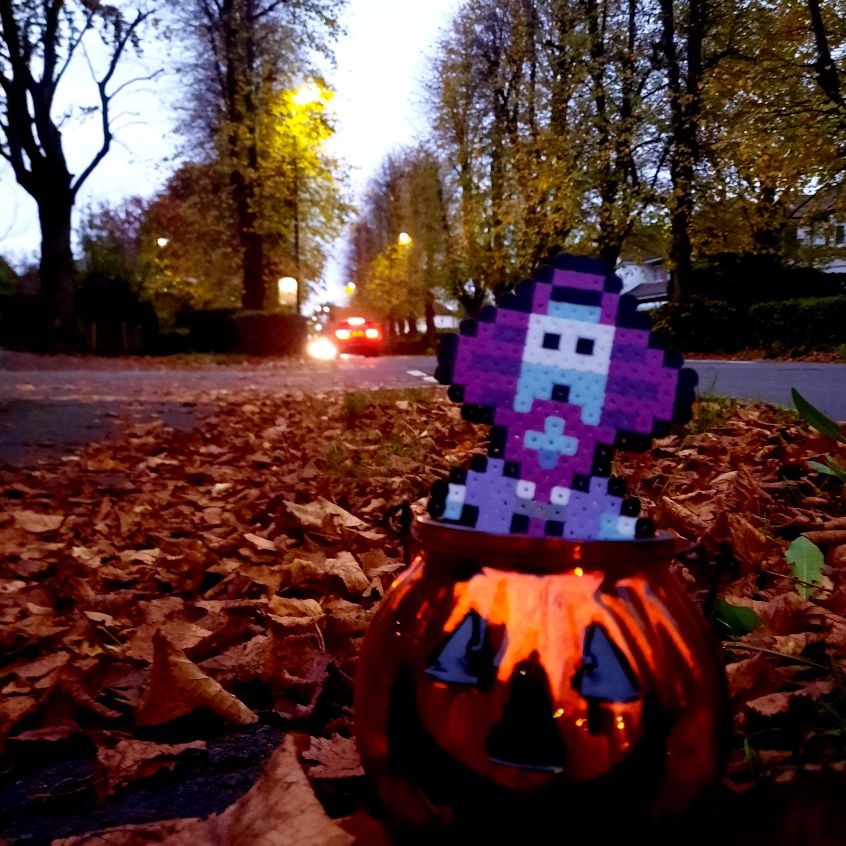 Physical sprite of the New Age Retro Hippie (Threed version) character from EarthBound / MOTHER 2, positioned inside a pumpkin container, outside in an autumn setting.