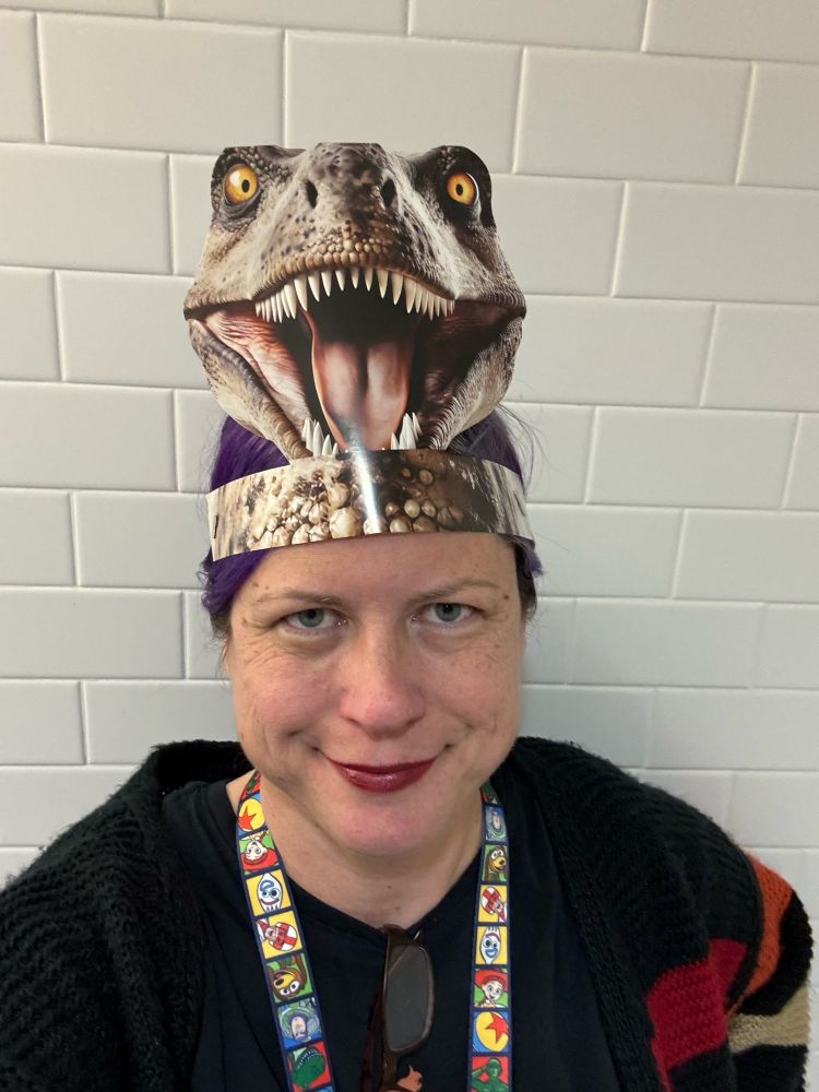 Picture of librarian wearing a dinosaur hat. 