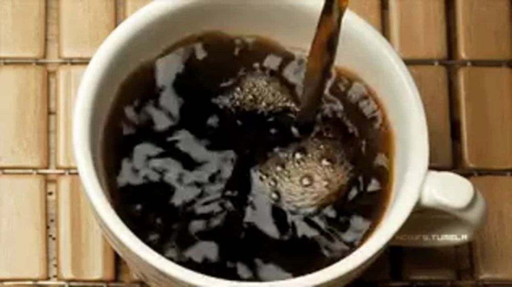 a cup of coffee is being poured into a cup on a table .