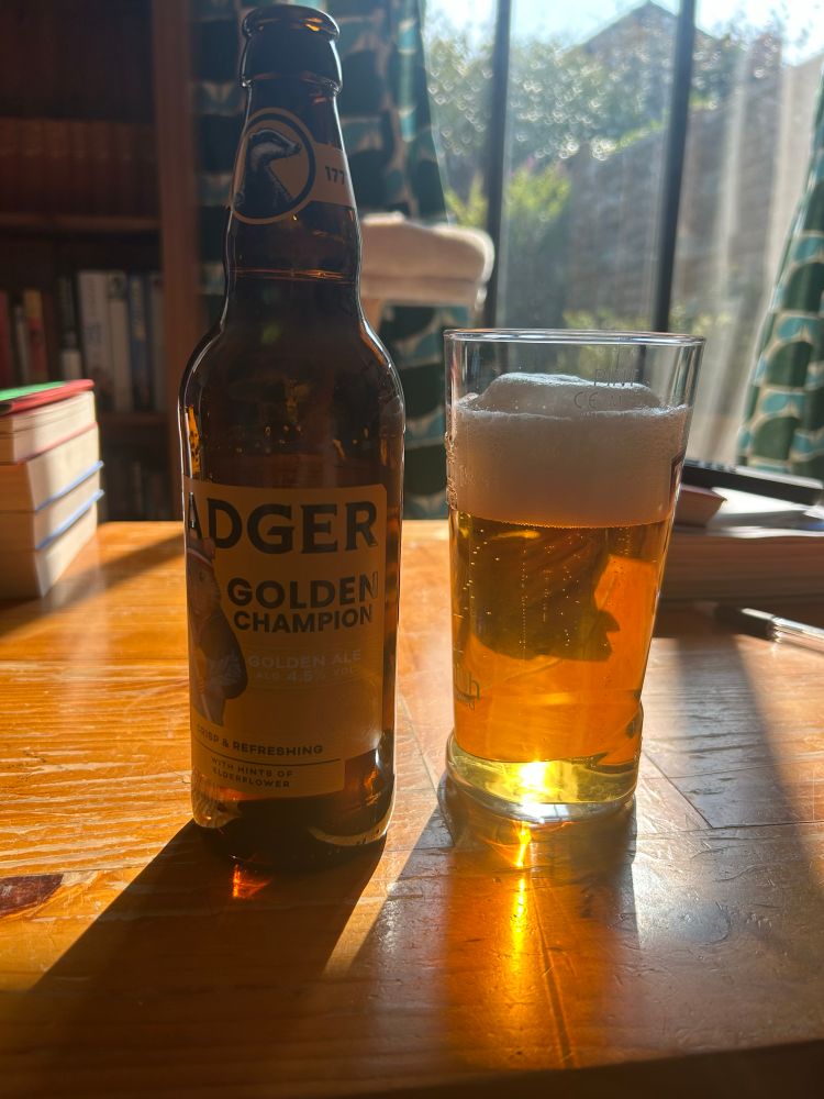 A poured bottle of Badger Golden Champion with the sun shining through it.