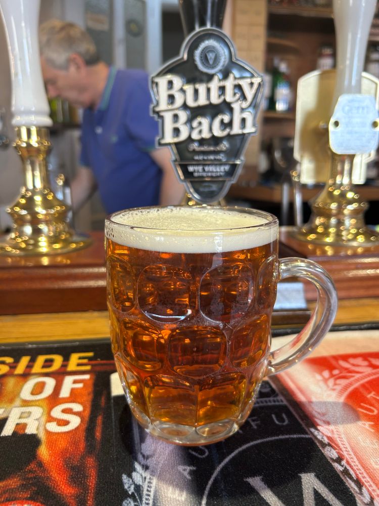 A pint mug of Butty Bach on the bar with the pump behind. Graham Ponting, landlord of the Berkeley Arms can be seen behind the bar.