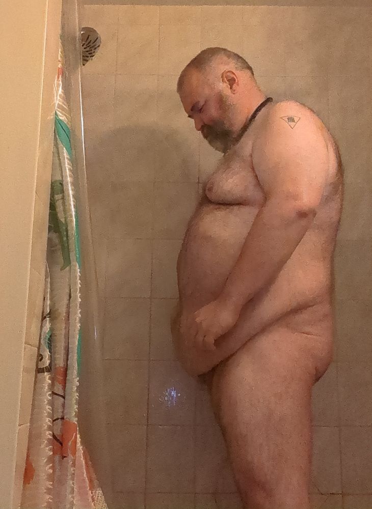 A fat naked man pissing in the shower