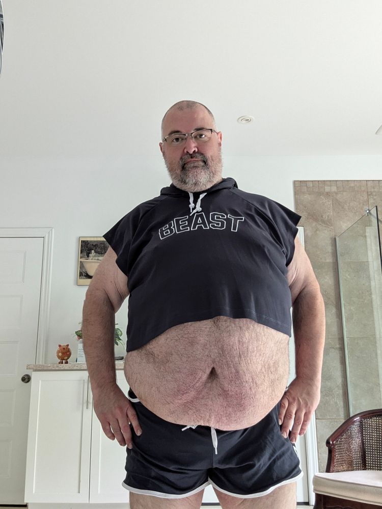 A fat man in a matching dark blue crop top and shorts. The top has the word Beast on it.
