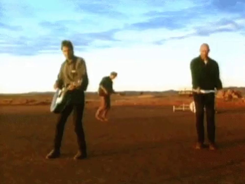 a group of men are playing guitars in the desert