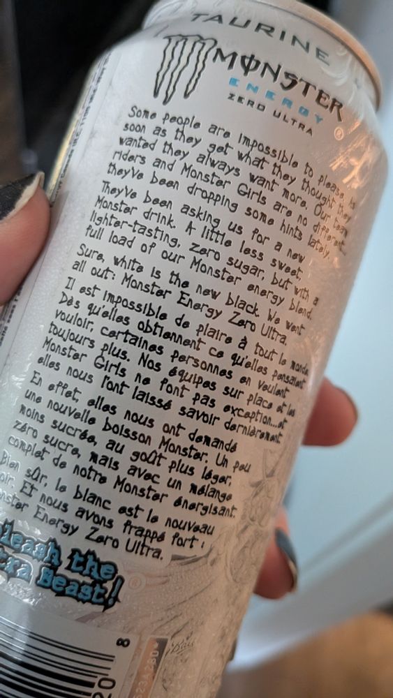 Side of a white can of monster energy "Zero Ultra". There's an inscrutable set of paragraphs i guess explaining why this flavour exists? It says that "Monster Girls have been dropping some hints". The French version of the text leaves the English term "Monster Girls" unlocalized