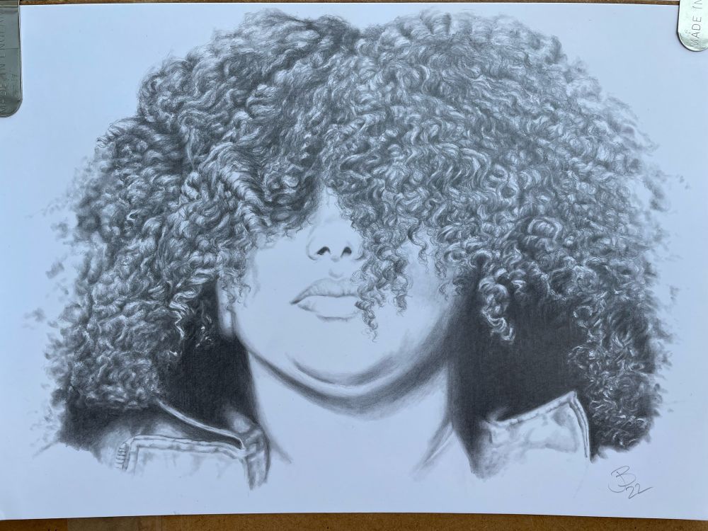 Photo of a portrait completed in pencil on Bristol board. My favourite medium to work with. The portrait is of a covered face, only the nose, mouth & chin are visible due to the amount of tight curly hair. Have I mentioned that I love drawing hair? I do love drawing hair