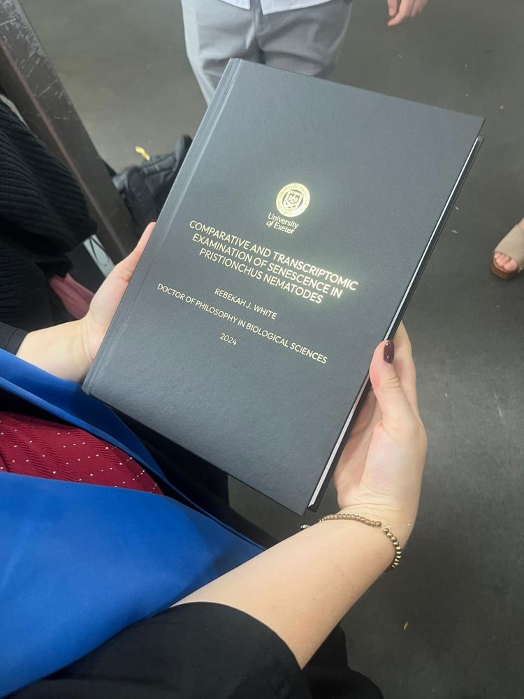 Rebekah holding her PhD thesis with title: Comparative and Transcriptomic examination of senescence in Pristionchus nematodes. 