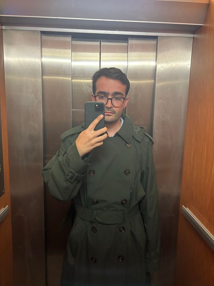 Soy yo con una gabardina verde en un ascensor