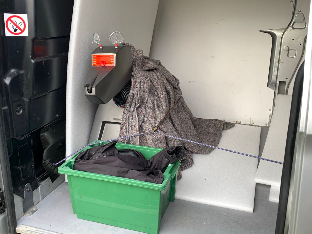 A robot dog, securely braced in the back of a van