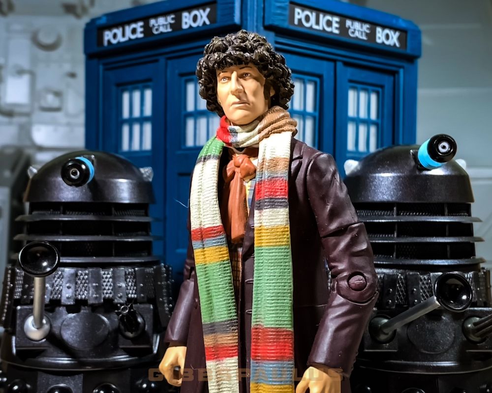 Tom Baker as Doctor Who, with multicoloured scarf, two metallic Daleks, and the big, blue TARDIS time machine. All are toys