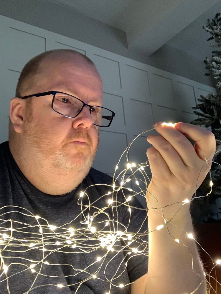 A bald, cuddly man, staring at a string of LED lights