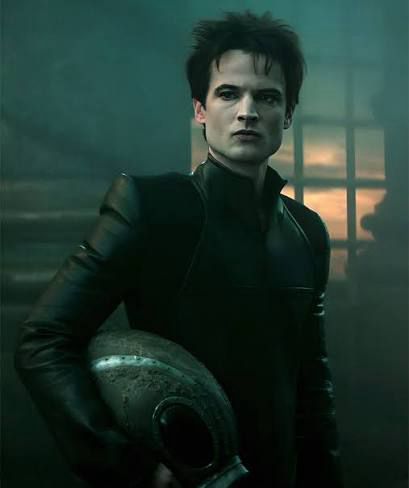 Actor Tom Sturridge: tall, thin, pale, dark hair. Dressed in black, with an enigmatic expression.