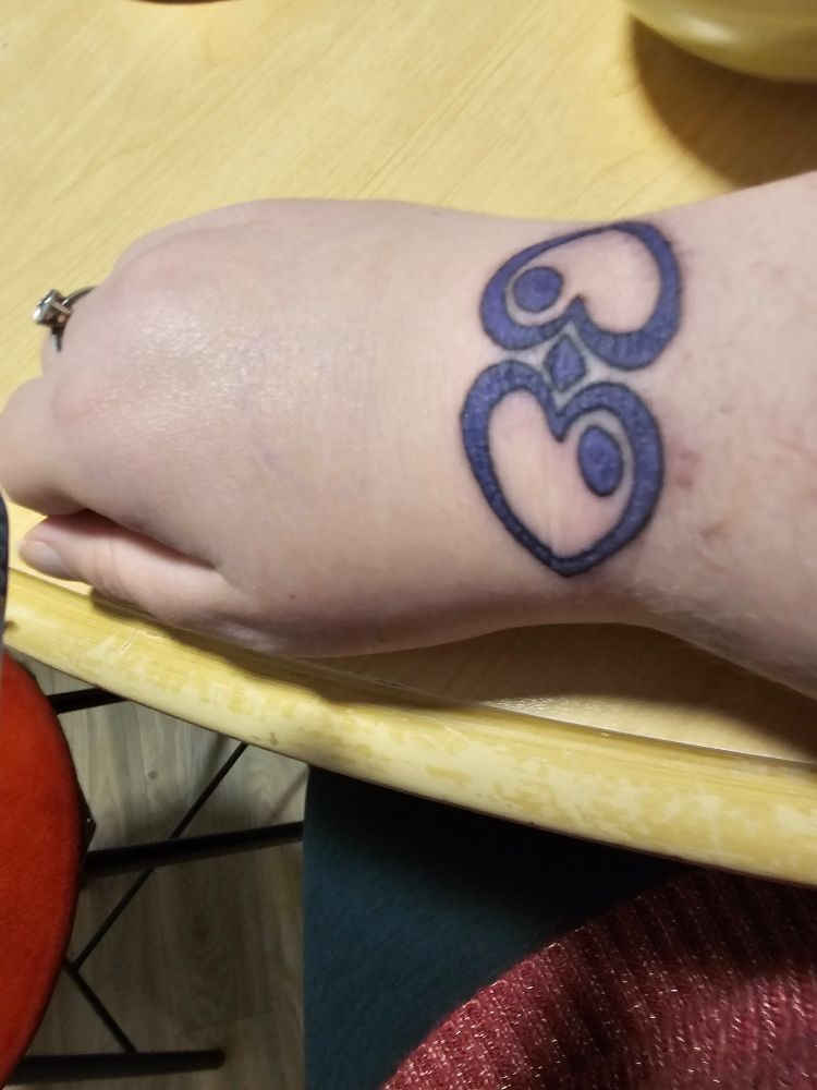 A picture of my hand with a symbol resembling two purple hearts tattooed onto it