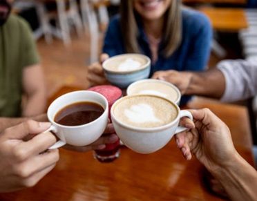 Image of group with cups of coffee toasting cheers