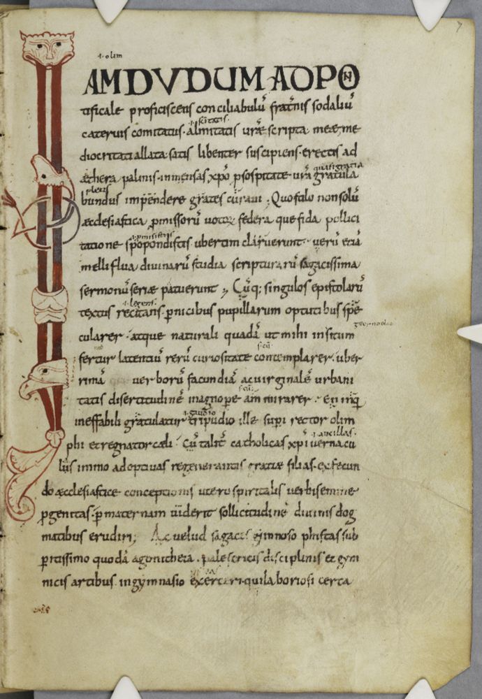 Manuscript page in black ink with long initial I in dark read with beast heads running down the left margin, and heavy black capitals for the top line.