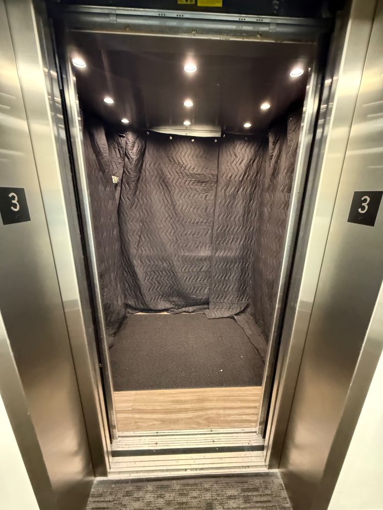 Elevator with all the walls covered by those big cloths. These are black.