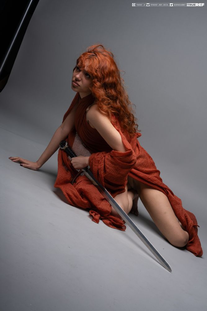 Pose reference of a woman draped in fabric holding a sword. 
