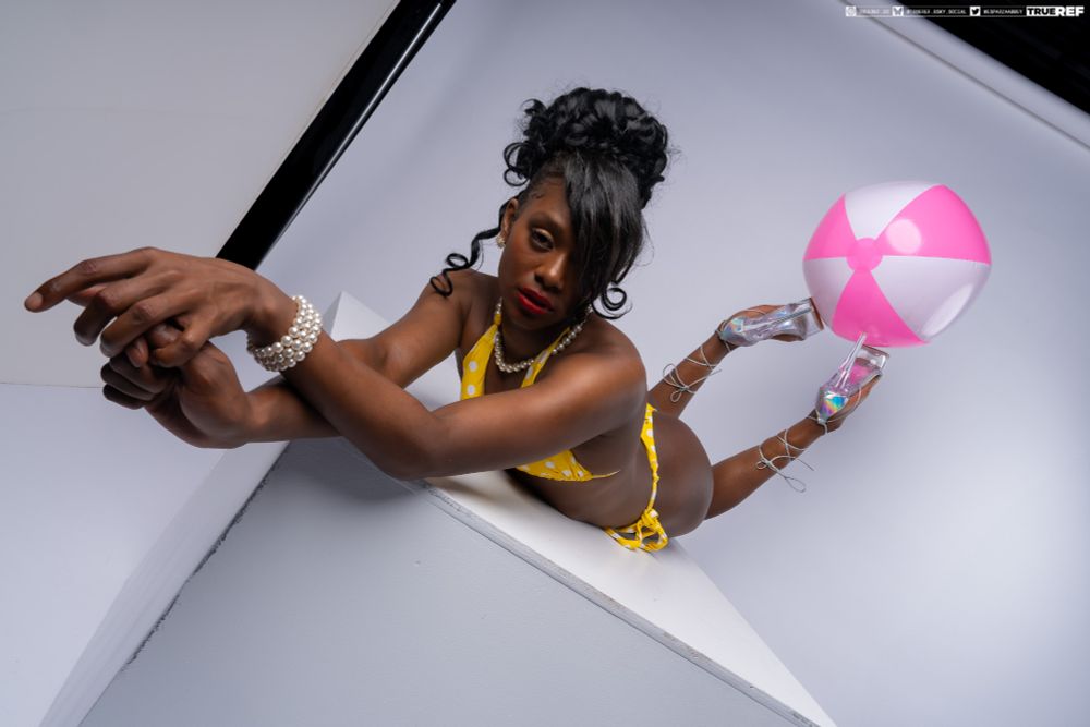 art pose reference of a woman in a yellow bikini laying with a pink beach ball.