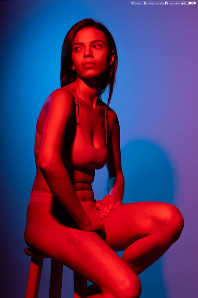 art reference of a woman bathed in red light sitting on a stool.