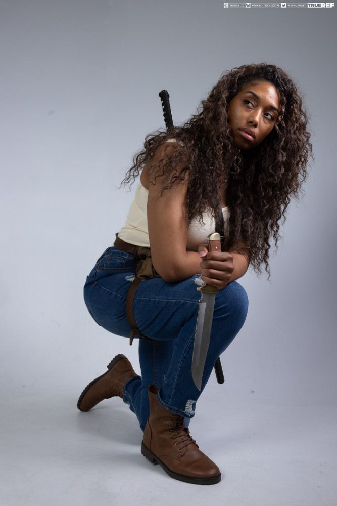 Pose reference of a woman crouching with a knife. 
