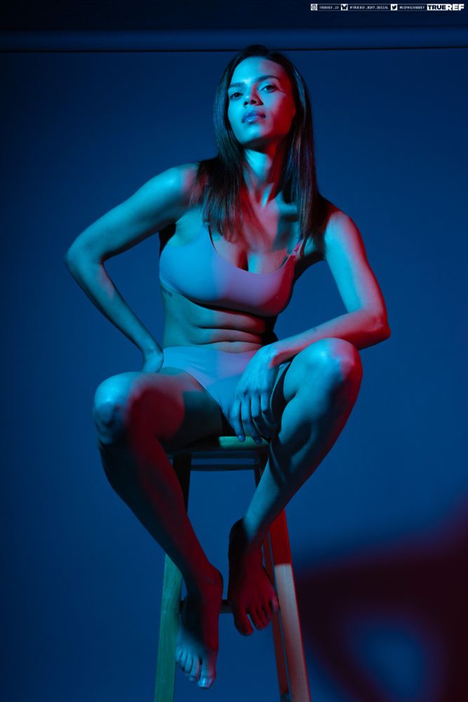 art reference of a woman bathed in blue and red light sitting on a stool.