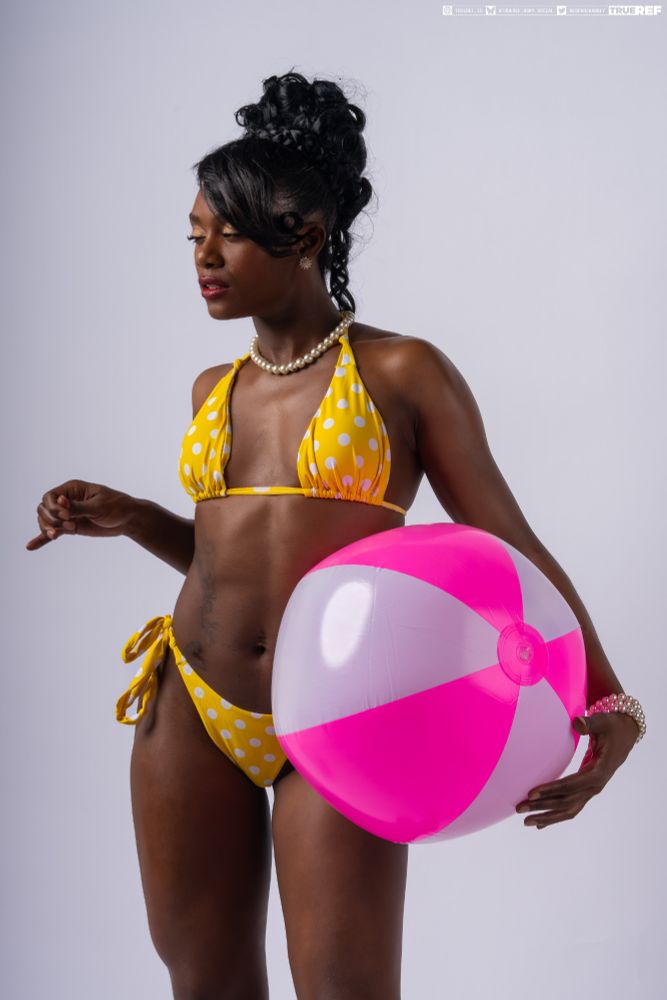 art pose reference of a woman in a yellow bikini standing holding a pink beach ball. 