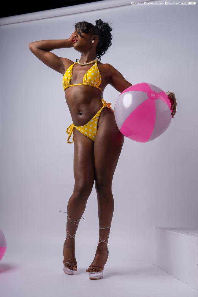 art pose reference of a woman in a yellow bikini standing holding a pink beach ball. 